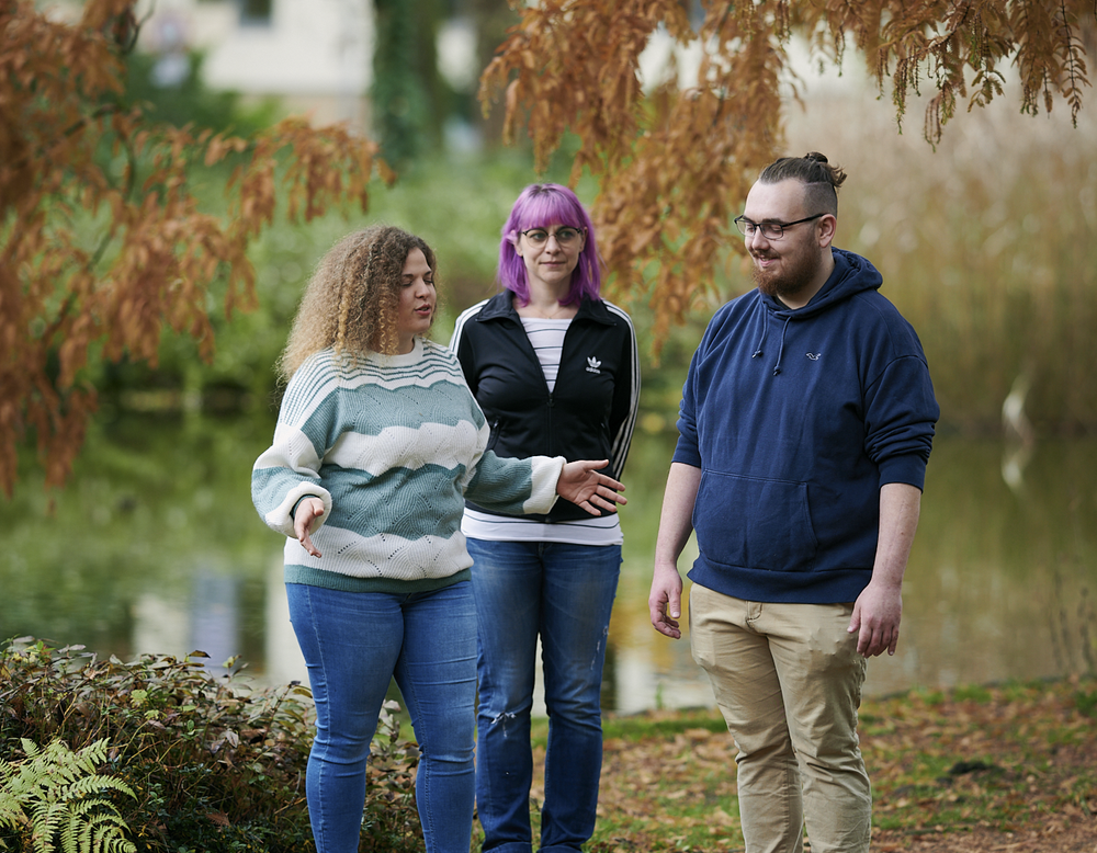 Achtsamer Spaziergang mit drei Menschen im Park.